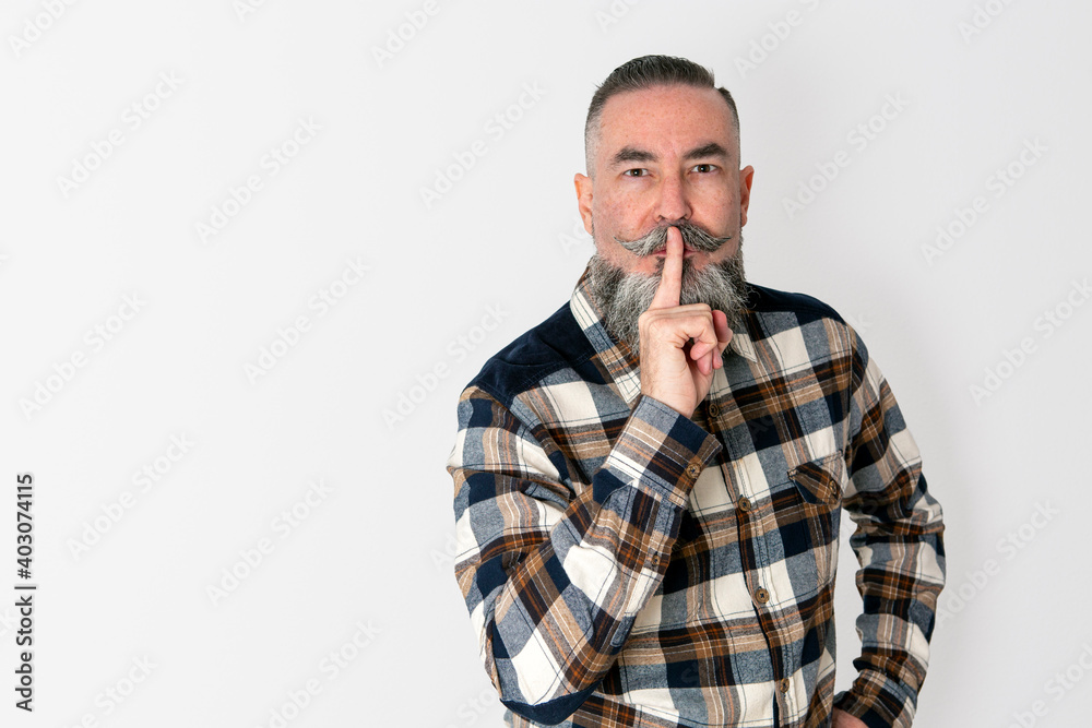 bearded man, retro style plaid shirt, set on white background. He puts his index finger to the corner of his lips making the gesture of ordering silence, silence concept bearded man, retro style plaid shirt, set on white background. He puts his index finger to the corner of his lips making the gesture of ordering silence, silence concept