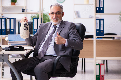 Old male employee holding moneybag in retirement concept