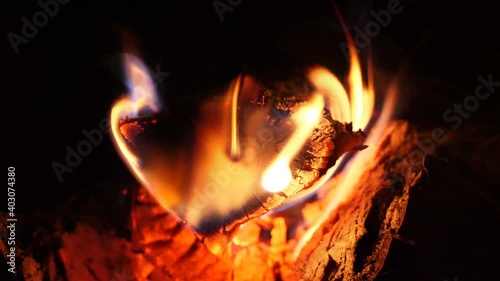 Fire is burning in the fireplace. Warmth and home comfort. Bright fire flames in dark hearth. Looped closeup view of burning wood and red coal