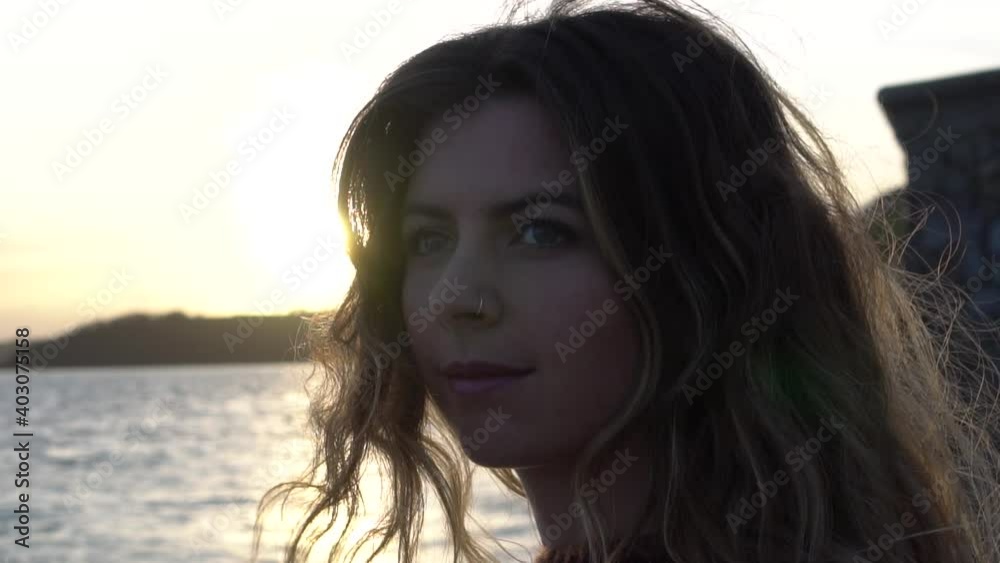 Girl looks past the camera on the beach in the sunset Girl looks past the camera on the beach in the sunset