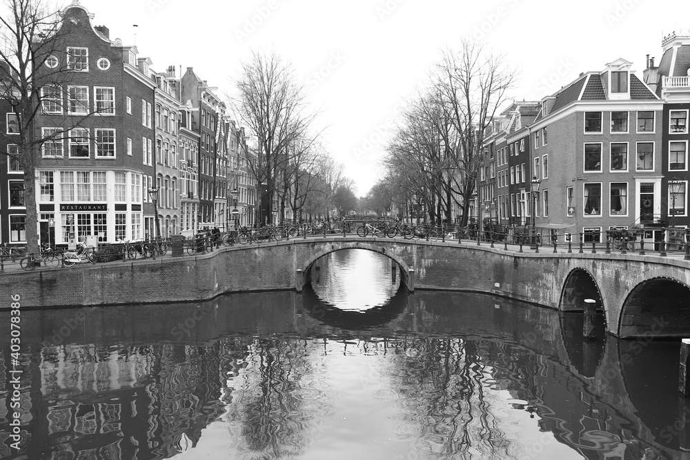 Cityscape Amsterdam Canal with Bridge, Houses, Bicycles and Winter Trees in Black and White