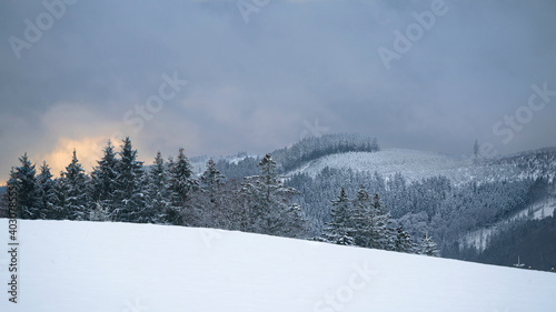 Snowy landscape on a peak of Sauerland mountains. Snow covered forests near and far. The sun shines orange in the evening. Taken in the village of Wasserfall near Bestwig. photo