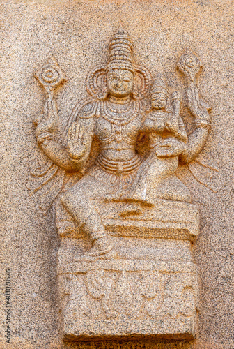 Hampi, Karnataka, India - November 4, 2013: Hazara Rama Temple. Closeup of beige stone sculptures of Vishnu with Lakshmi on his lap.