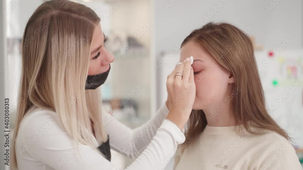 Beauty salon. An eyebrow specialist wipes a woman's eyebrows with a cotton pad. Beauty salon. An eyebrow specialist wipes a woman's eyebrows with a cotton pad.