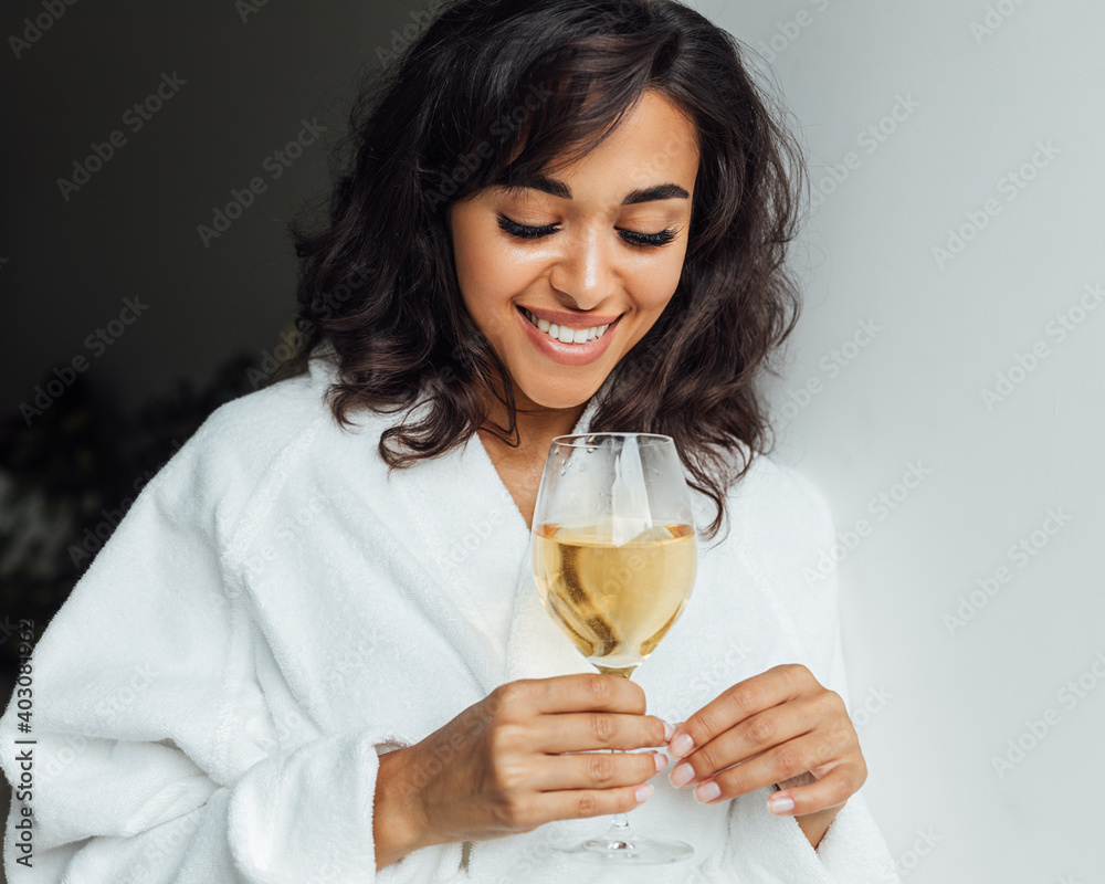 Beautiful woman relaxing at home. Smiling female looking at bocal with wine. Beautiful woman relaxing at home. Smiling female looking at bocal with wine.