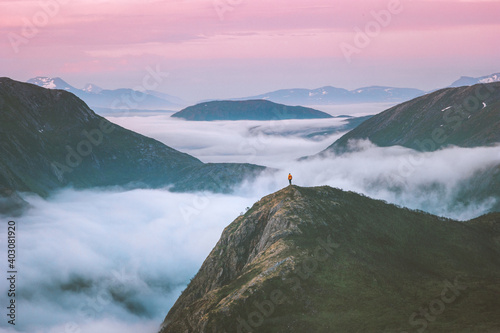Traveler hiking above mountain clouds enjoying Norway sunset landscape travel adventure lifestyle vacation outdoor epic trip