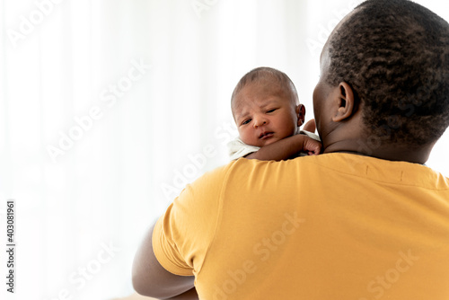 Close up on face of baby newborn son is half-African halt-Thai on father's shoulder with white background, to baby newborn and family concept.