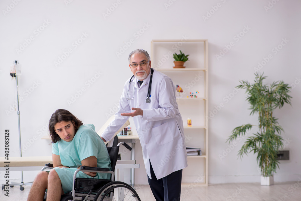 Young male patient in wheel-chair and experienced doctor traumatologist Young male patient in wheel-chair and experienced doctor traumatologist