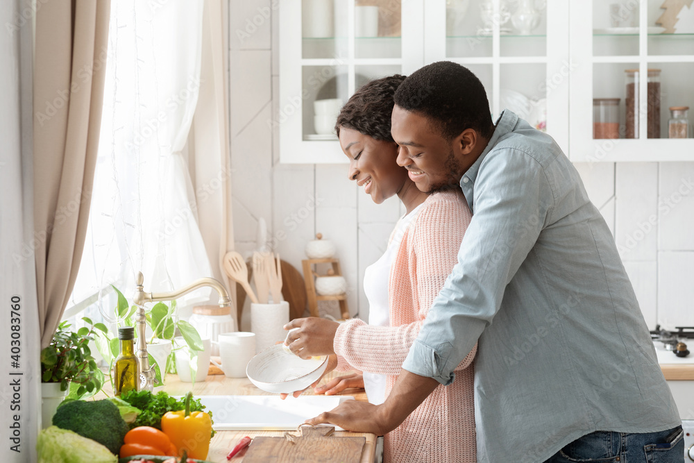 Romantic Black Couple Cleaning Dishes And Bonding Together In Kitchen