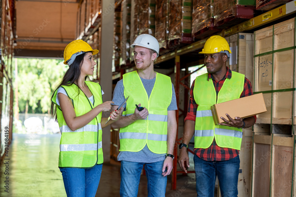 Distribution warehouse manager in discussion with colleagues in a large distribution warehouse. Distribution warehouse manager in discussion with colleagues in a large distribution warehouse.