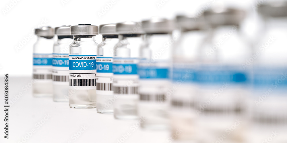 Panoramic photo of a lot ampoules with COVID-19 corona virus vaccine for injection on white background. Coronavirus vaccine manufacture, worldwide vaccination and healthcare concept