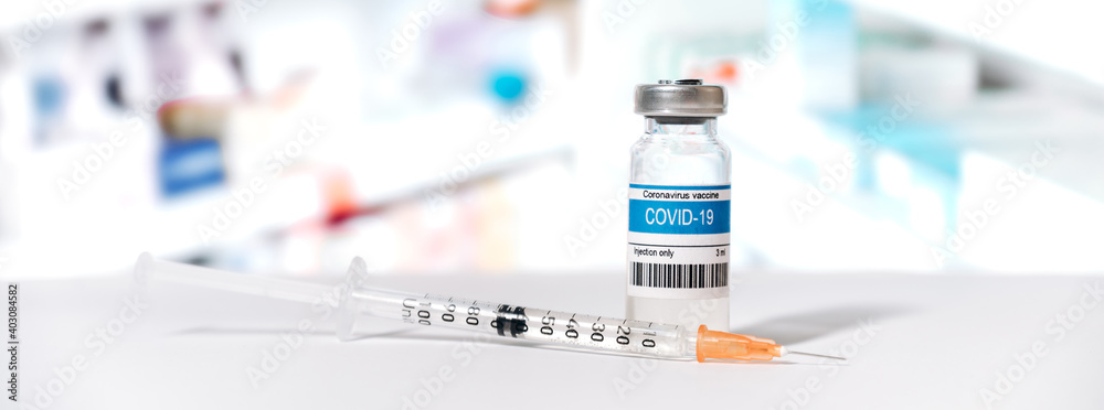 Panoramic photo of an ampoule with a coronavirus vaccine and a syringe in a laboratory. COVID-19 worldwide vaccination. Medicine and health prevention concept