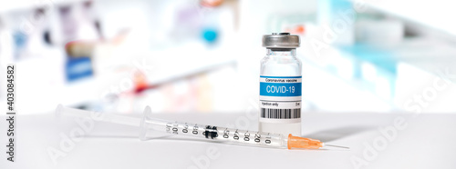 Fototapeta Naklejka Na Ścianę i Meble -  Panoramic photo of an ampoule with a coronavirus vaccine and a syringe in a laboratory. COVID-19 worldwide vaccination. Medicine and health prevention concept