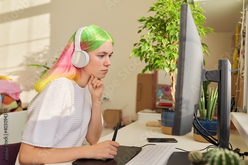 Fotografie, Tablou Girl teenager artist in headphones drawing on computer using graphics tablet
