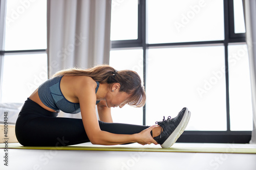 woman in sportswear doing fitness stretching exercises at home in bright room. sport, healthy lifestyle and recreation concept.