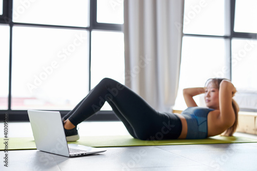 asian woman doing pelvic lift abdominal exercise on the floor, in bright room studio. sport, workout, fitness concept