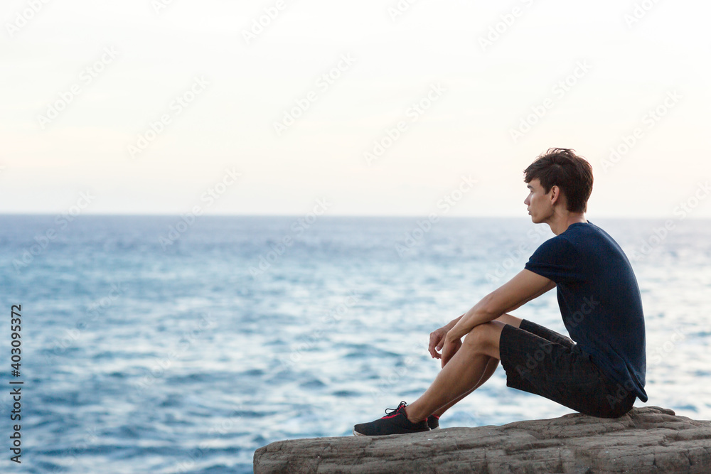 Young man sitting alone watching the ocean view.