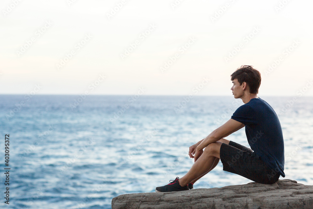Young man sitting alone watching the ocean view. Young man sitting alone watching the ocean view.