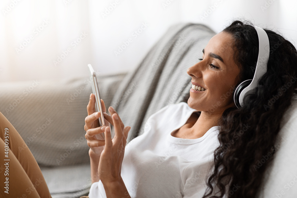 Happy young woman in headphones watching movie on phone Happy young woman in headphones watching movie on phone