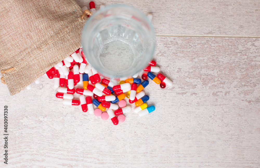 Glass of water and colourful pills on table. Glass of water and colourful pills on table.