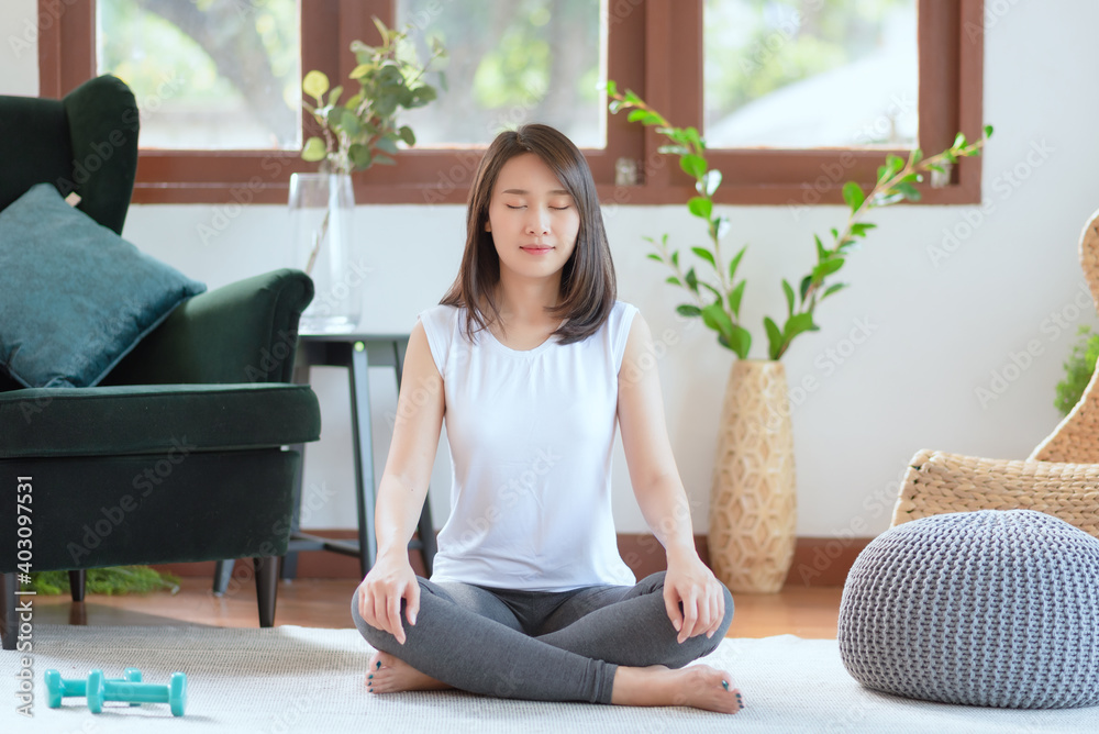 Beautiful asian woman keep calm and meditates while practicing yoga at home for healthy trend lifestyle Beautiful asian woman keep calm and meditates while practicing yoga at home for healthy trend lifestyle
