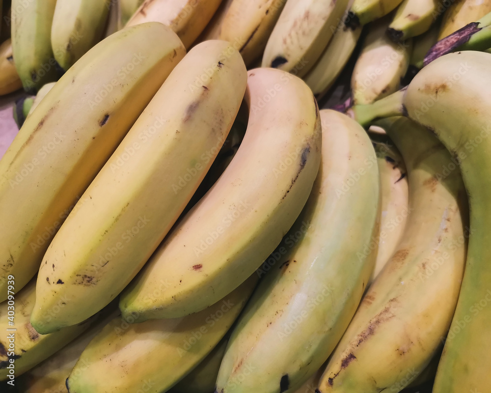 bananas in a pile at market. Yellow texture background.