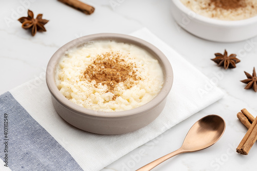Creamy rice pudding with cinnamon in bowl on white marble table
