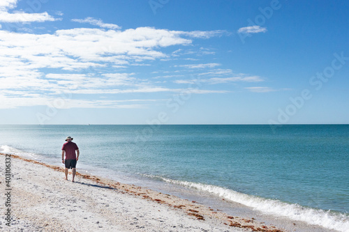 60 year old man walks along beach in Florida photo