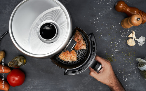 фотографія Unrecognizable man hand cooking skinless chicken breast with spices in an air fr