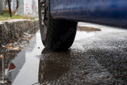 Reflection of a car wheel in a puddle, detail of an autumnal and rainy scene. Selective focus