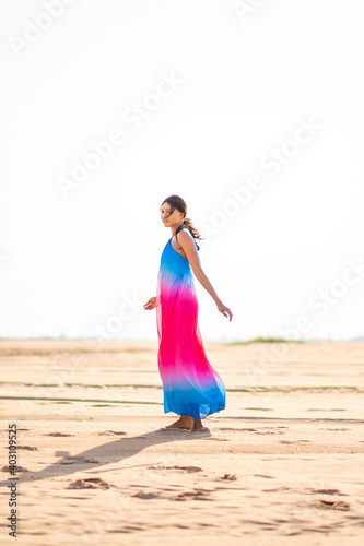 beautiful african woman at a beach wearing a colorful dress having fun on the sand