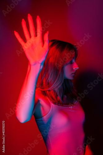 Anonymous woman covering face with hand in red neon light