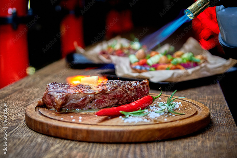 Master chef cooking barbecue Beef Grilled steak meat with fire flames on wooden table Master chef cooking barbecue Beef Grilled steak meat with fire flames on wooden table