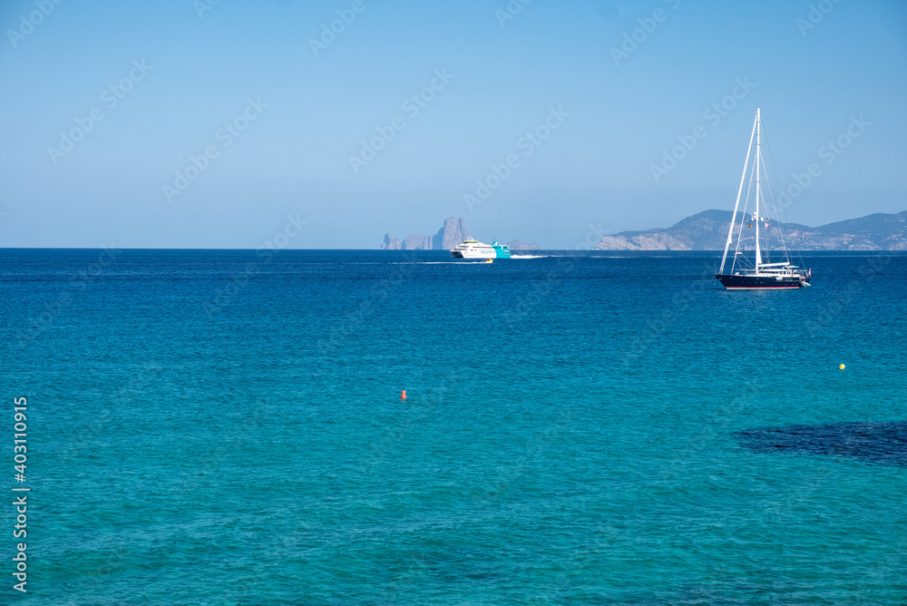 idilico Paisaje marino español con mar, cielo azul, barcos de recreo y orilla de playa en isla