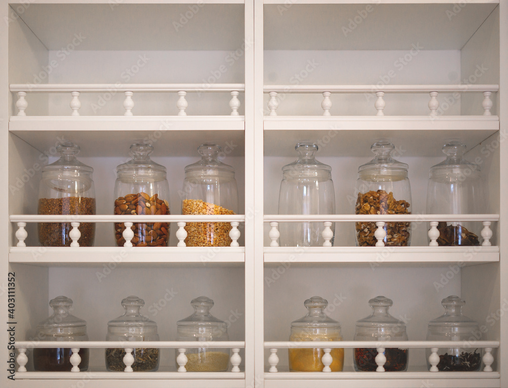 kitchen cabinet with open shelves, on which there are glass jars with spices, cereals and seasonings kitchen cabinet with open shelves, on which there are glass jars with spices, cereals and seasonings