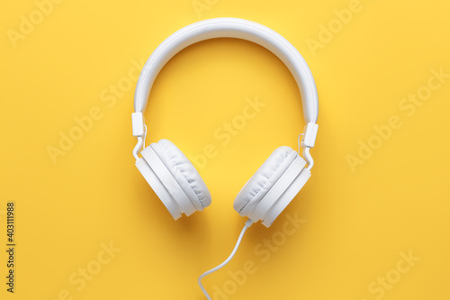 Modern white headphone on yellow background. Music concept.