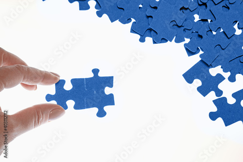 puzzle pieces are scattered on a white background, difficult task, the hand connects the puzzle pieces