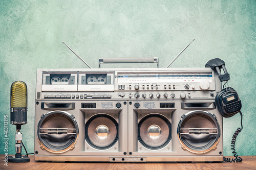 Retro ghetto blaster stereo radio cassette tape recorder boombox from circa 80s, old microphone, headphones front concrete wall background. Nostalgic music concept. Vintage style filtered photo