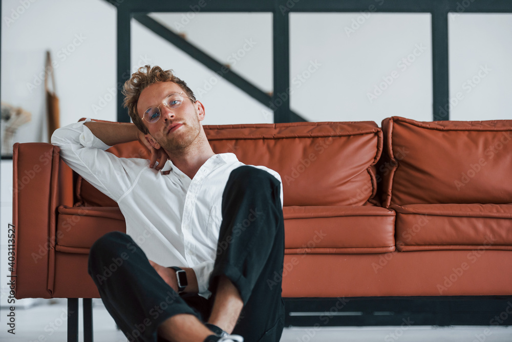Having a rest. Caucasian young guy in elegant white shirt indoors at home Having a rest. Caucasian young guy in elegant white shirt indoors at home