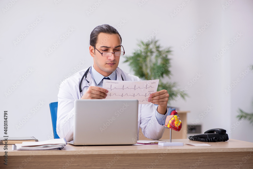 Young male doctor cardiologist looking electrocardiogram Young male doctor cardiologist looking electrocardiogram
