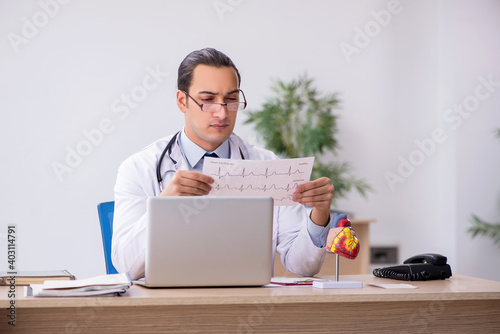 Young male doctor cardiologist looking electrocardiogram