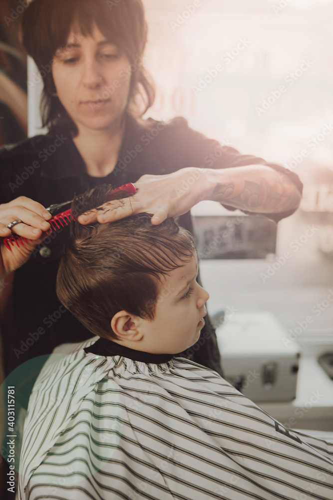Fototapeta premium The work of the barbershop. Haircut of a boy in a barbershop. Children's haircut