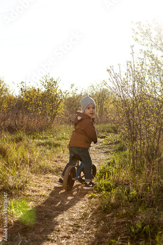 A boy rides a balance bike in a clearing. Spring mood. Sun