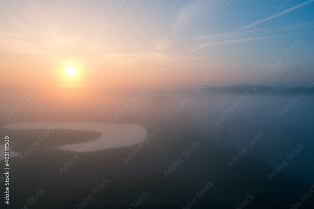Wschód słońca we mgle nad wodą