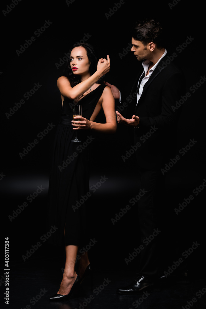 rude woman in dress holding glass of champagne and showing middle finger to man in suit on black rude woman in dress holding glass of champagne and showing middle finger to man in suit on black