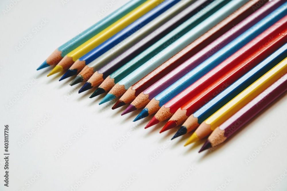 Colorful wooden crayons on the piece of white paper. Set of colored wooden pencils close-up. White background Colorful wooden crayons on the piece of white paper. Set of colored wooden pencils close-up. White background