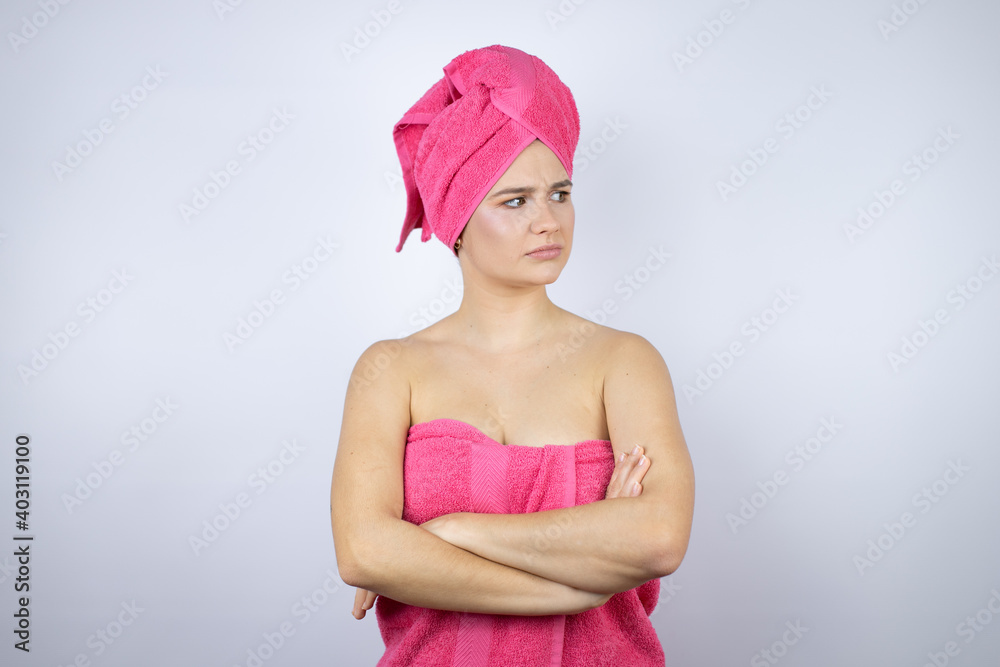 Young beautiful woman wearing shower towel after bath standing over isolated white background thinking looking tired and bored with crossed arms Young beautiful woman wearing shower towel after bath standing over isolated white background thinking looking tired and bored with crossed arms