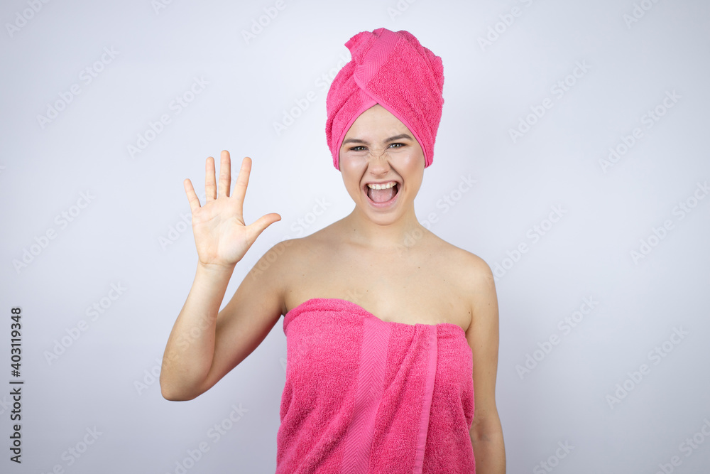 Young beautiful woman wearing shower towel after bath standing over isolated white background showing and pointing up with fingers number five while smiling confident and happy Young beautiful woman wearing shower towel after bath standing over isolated white background showing and pointing up with fingers number five while smiling confident and happy