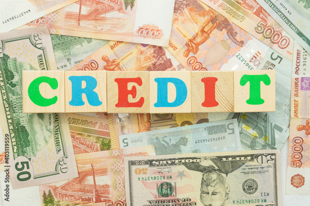 The inscription credit in multicolored cubes on the background of banknotes euro dollars rubles The inscription credit in multicolored cubes on the background of banknotes euro dollars rubles