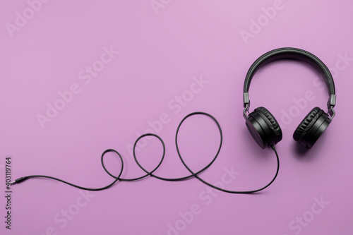 Stylish modern black headphones on purple background.